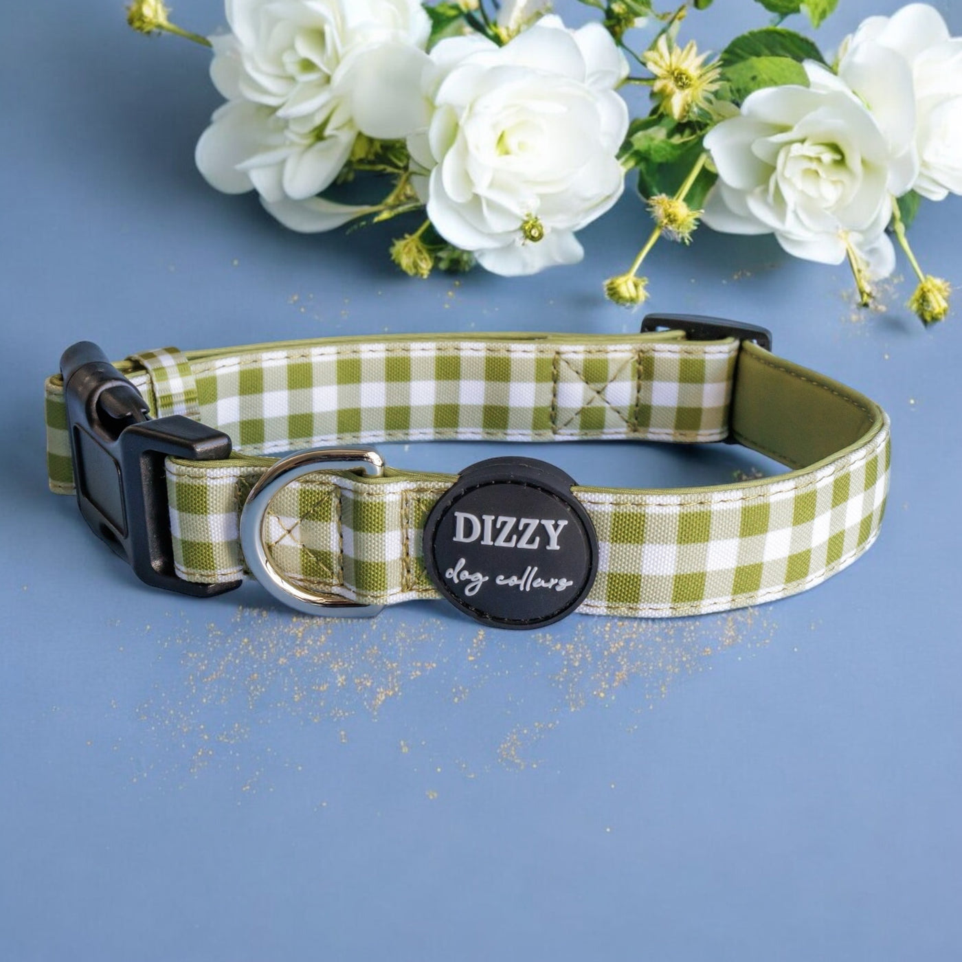 The image features a green and white checkered dog collar on a navy blue background, accented by white roses and gold glitter. The collar is labeled "Dizzy Dog Collars," and the overall composition highlights the collar with an elegant floral touch.