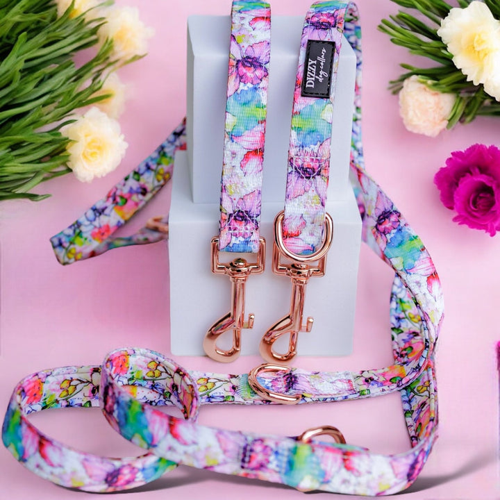 Bright and colourful floral dog leash set featuring a vibrant design with rose gold hardware. The leash is displayed against a pink background with decorative flowers, showcasing its eye-catching and stylish appearance.