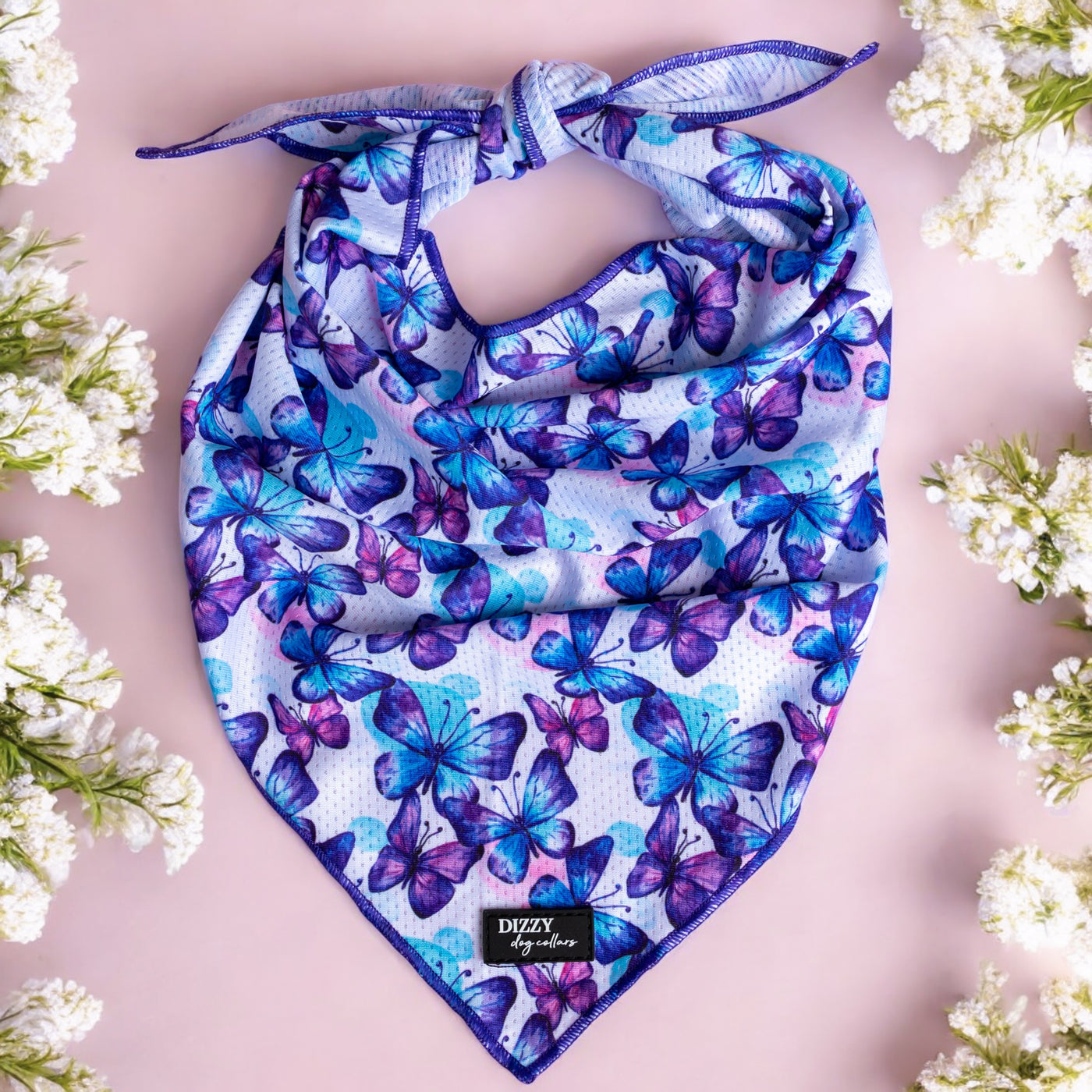 Butterfly Bandana  Description: A charming dog bandana featuring a vibrant pattern of blue and purple butterflies on a light background. The edges are neatly stitched in a matching blue thread.