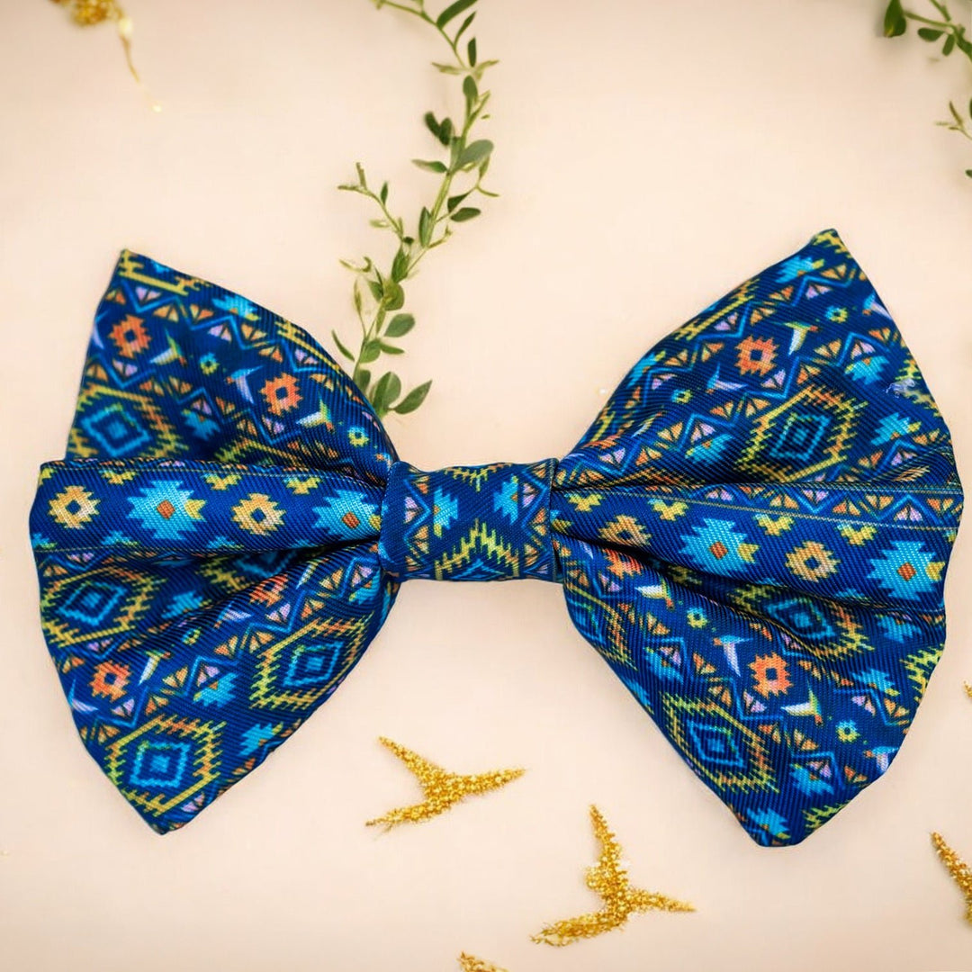 Description: This vibrant bow tie features an intricate Aztec-inspired pattern in bold colours of blue, orange, and green. Perfect for adding a pop of style to your pet's look, it easily attaches to any collar with its secure fastening. Made from durable, high-quality fabric, this bow tie is ideal for both special occasions and everyday wear, ensuring your furry friend stands out with a fashionable flair.