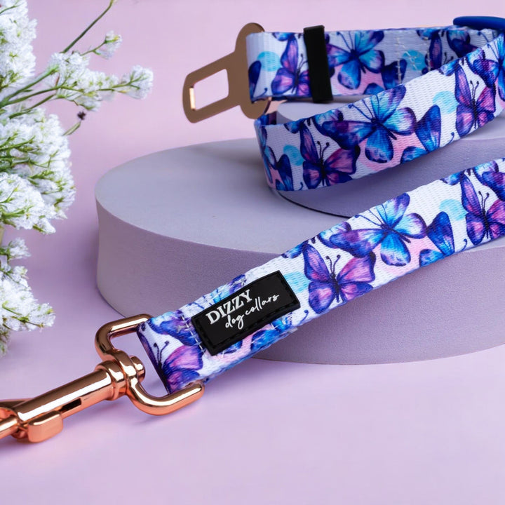 Description: A car restraint tether for dogs, featuring the same butterfly design. It has a rose gold clasp and a universal seatbelt clip for safe and secure travel.