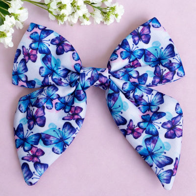 Butterfly Sailor Bow Tie by Dizzy Dog Collars This elegant sailor bow tie features a stunning pattern of blue and purple butterflies, perfect for adding a touch of style to your pet's look. Made from high-quality fabric, it is designed to be both durable and comfortable. Ideal for special occasions or everyday wear, this bow tie can be easily attached to any collar, making your furry friend look adorable and chic.