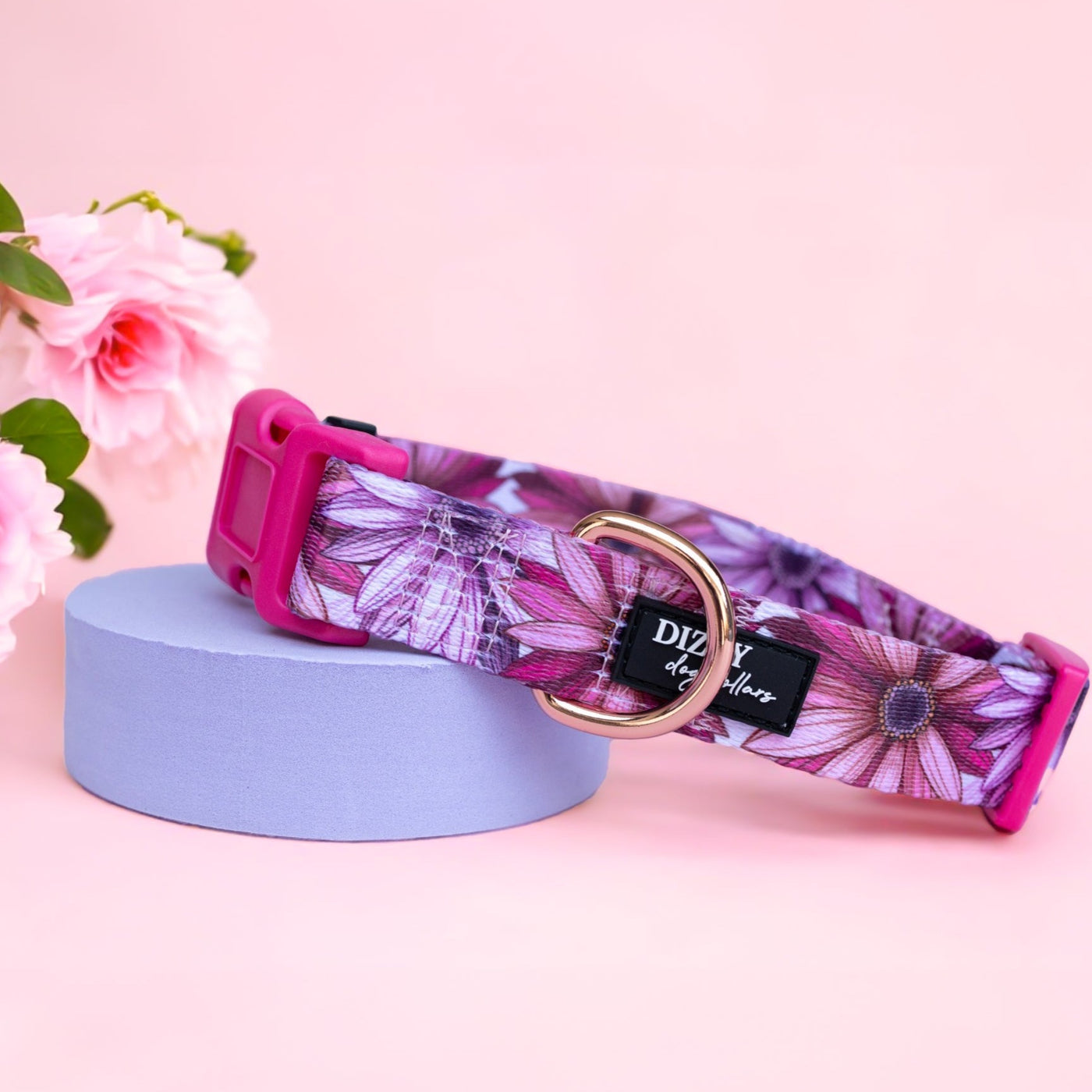 Perfect Petals Dog Collar  Description: This dog collar features a delightful floral pattern in shades of pink and purple, accented with a rose gold D-ring and buckle. The collar is adjustable, ensuring a comfortable fit for your pet. Ideal for adding a touch of elegance to your dog's everyday look.