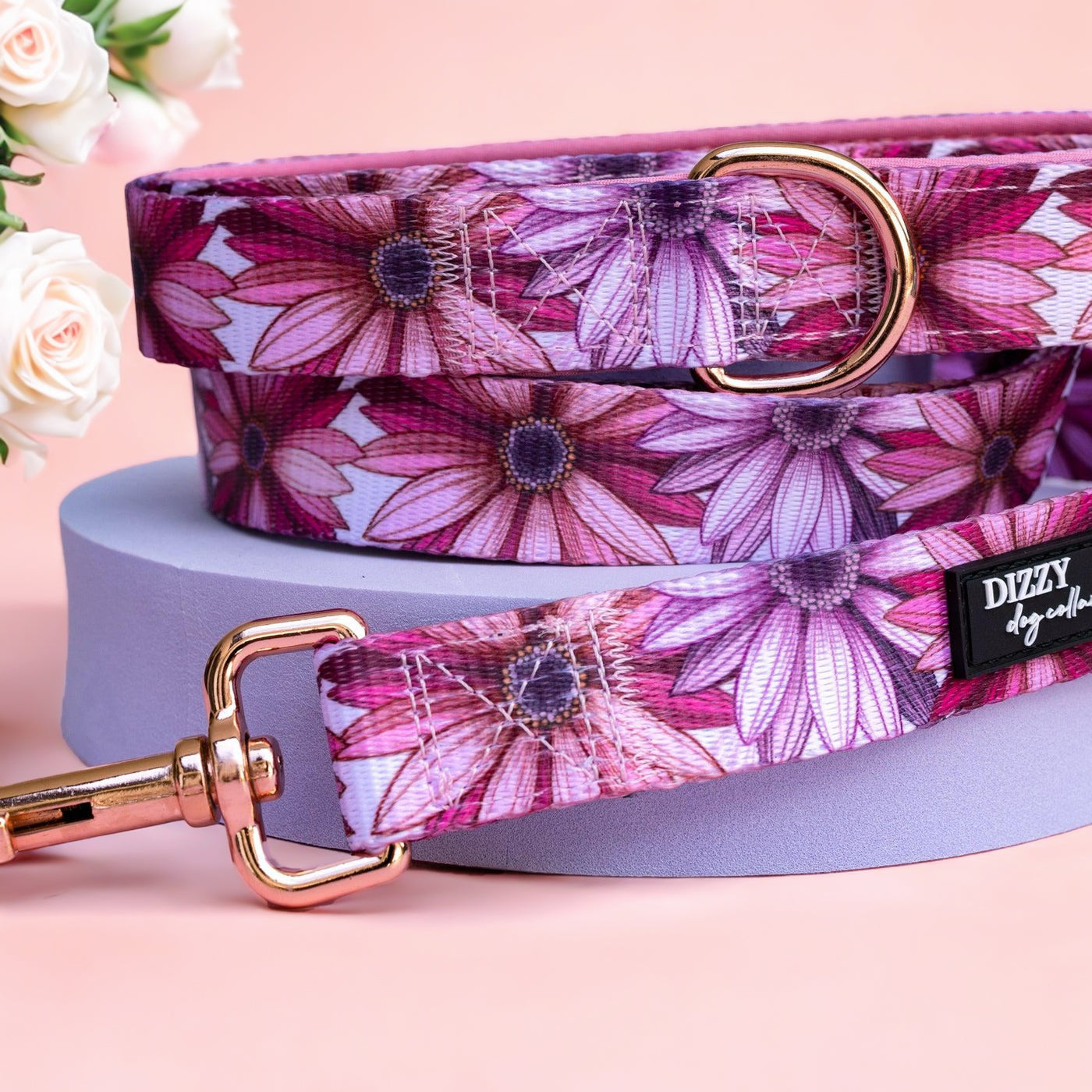 Perfect Petals Dog Leash by Dizzy Dog Collars This elegant dog leash features a delightful floral pattern in shades of pink and purple. Designed for both style and durability, it includes a rose gold D-ring and clasp for secure attachment. The leash is made from high-quality fabric, ensuring it can withstand daily use while adding a touch of sophistication to your pet's walks. Ideal for pet owners who want their dogs to look chic and stylish.